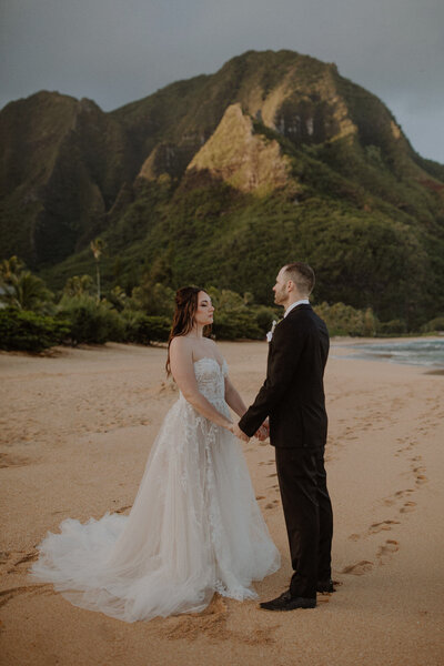 Couple stands on the beach in Kauai at sunrise