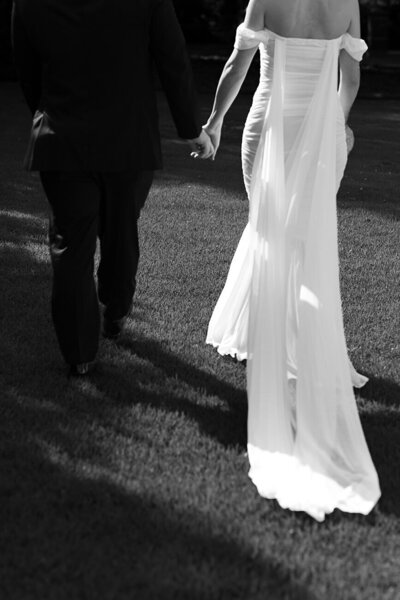 bride and groom  walking away while holding hands