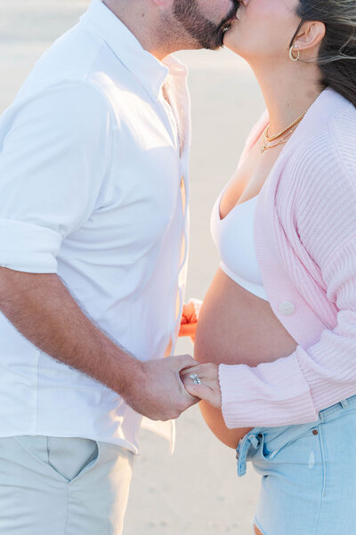 Maternity photos in Narragansett, RI of husband and wife kissing with pregnant belly sticking out