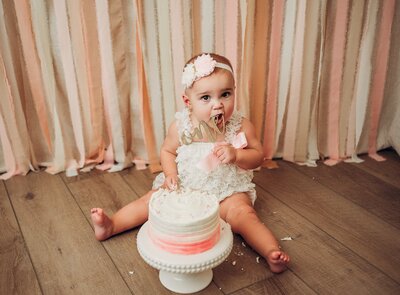 baby girl eating first birthday cake