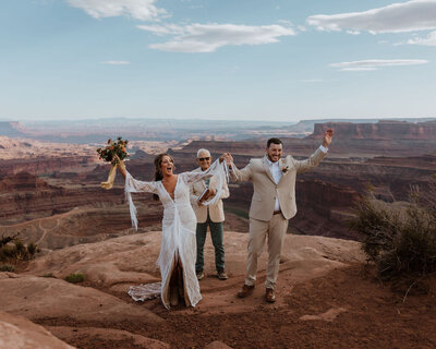 bride and groom holding hands and cheering after they just got married at deadhorse state park