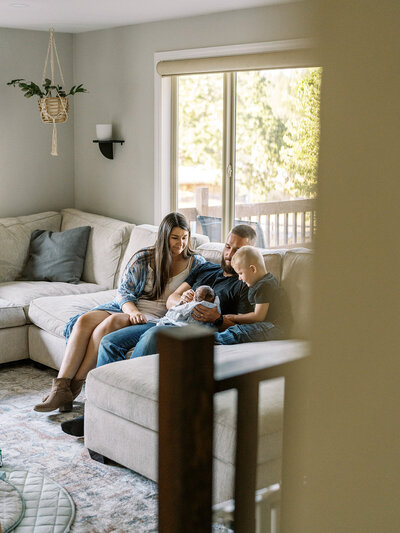 A family on their couch holding a newborn, representing a family photography portraits session. 
