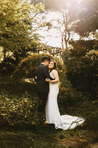 Sabrina and Tyler share romanticembrace in the gardens under the glowing sun at Hakone Gardens