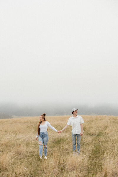 A man kissing his girlfriend in front of tall grass.