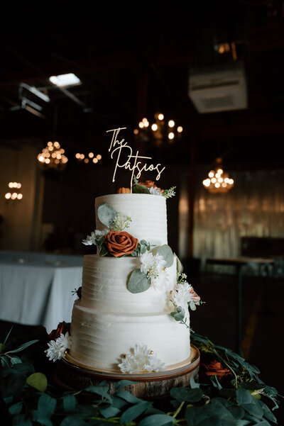 A three tiered white wedding cake with fall colored florals