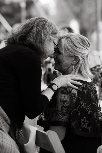 two women happy touching faces at a wedding reception black and white