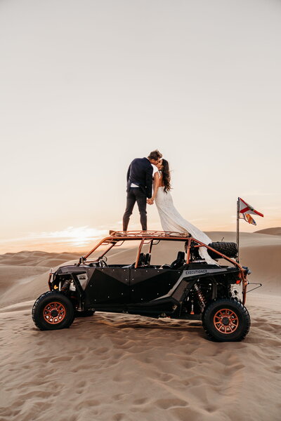 bride and groom standing on dune buggy