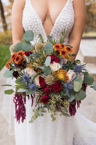 Vibrant autumn colored bouquet with bride in low cut dress