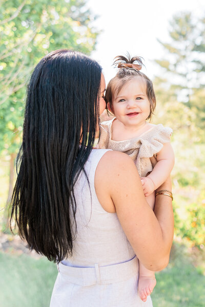 A tender moment of a mother holding and nuzzling her baby, who is smiling at the camera.
