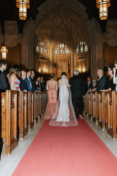 Bride walking with parents down the aisle at church