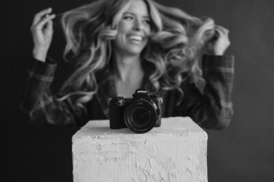 Holding her open laptop in one hand and fanning her hair with her other, Emily softly smiles at the camera.
