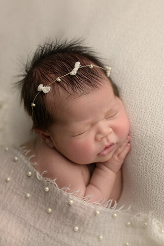 newborn baby boy swaddled in a blue knit blanket wearing a bonnet