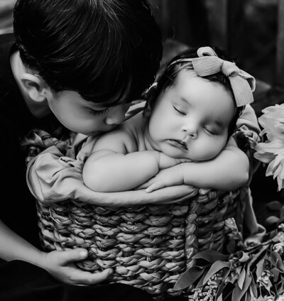 A heartwarming scene of a little boy kissing his baby sister gently. 