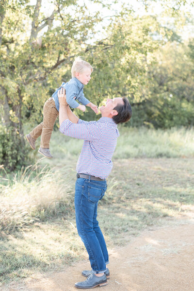dad lifts son into the air while laughing