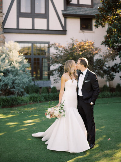 Bride and groom kissing outside a country club