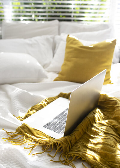 Bright, cozy setup with laptop on bed, representing flexibility and comfort in virtual RTT and transformation sessions