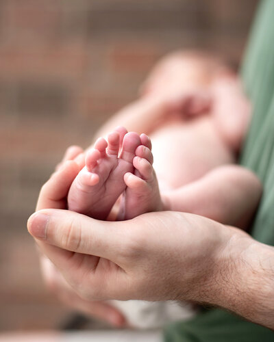 Newborn girl wearing a pink swaddle and beige mohair bonnet.