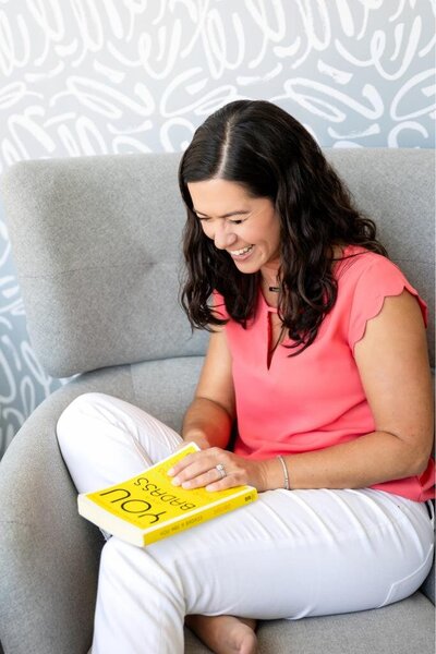Maria smiles and leaning on the sofa during a branding photoshoot, capturing a cozy and cheerful moment perfect for lifestyle photography.