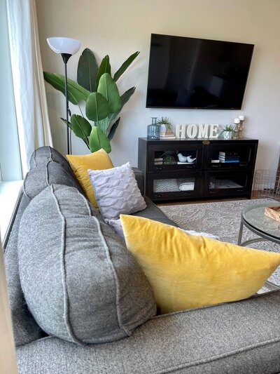 living room with grey couch and yellow pillows