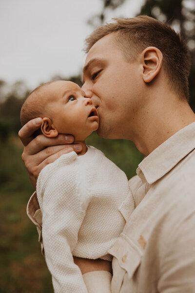 New dad kisses his newborn baby's cheeks
