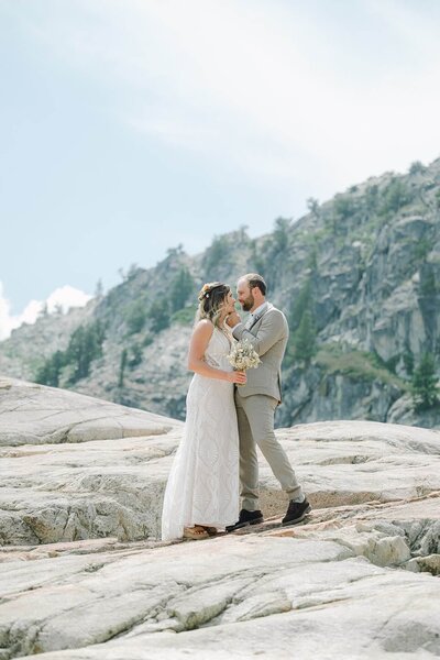 Newlyweds facing each other on a mountain of granite at White Wolf property in Alpine Meadows during summer wedding of those two World Cup ski racers