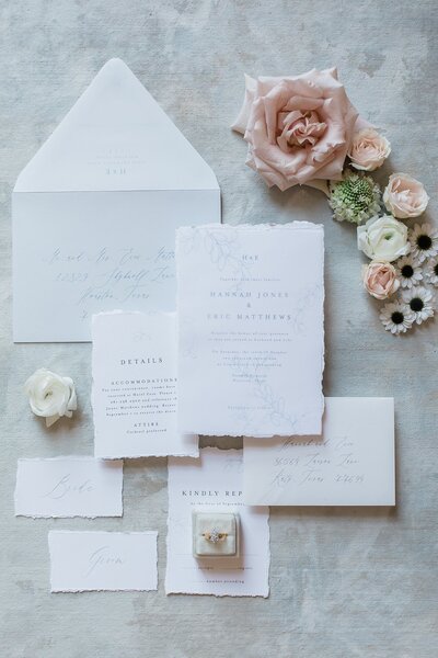 Flatlay of wedding invitations with flowers on a dusty blue mat for the Farmhouse wedding in Montgomery, Texas