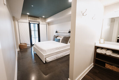 King size bed in a beautiful room with large windows and a door giving access to patio