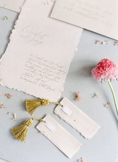 Rectangular wedding place cards with calligraphed vellum overlays and gold tassel accents