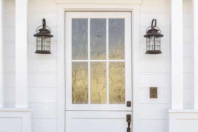 image of a white sided house with a dutch entry door and black lanterns