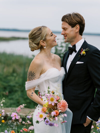 A couple embracing in front of the water at their Willow Inn wedding ceremony.