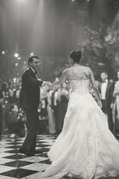A black and white photo depicting a high end wedding, and bride and groom dancing in Cipriani 42 while everyone gazes them.