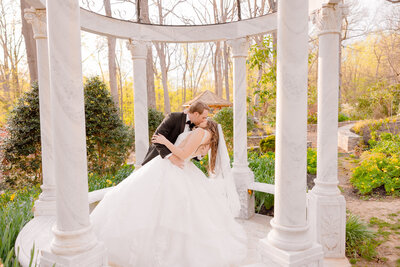 A couple shares a kiss under the gazebo and Gramercy Mansion Wedding Photographer snaps a photo