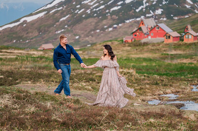 An engaged couple walking while holding hands during the midnight sun in Hatcher's Pass Alaska by JoLynn Photography, a destination wedding photographer