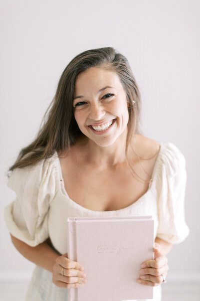 photo of Madison WI photographer Talia Laird Photography, the owner of Talia Laird Photography, holding a blush pink linen newborn album