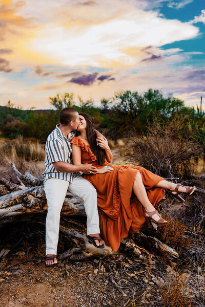 Couple kissing in the Arizona desert with cactus and mountain view during sunset session
