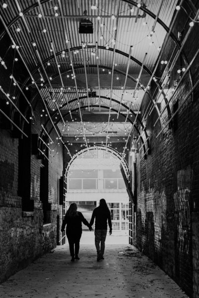 couple walking through artsy twinkly light alleyway 