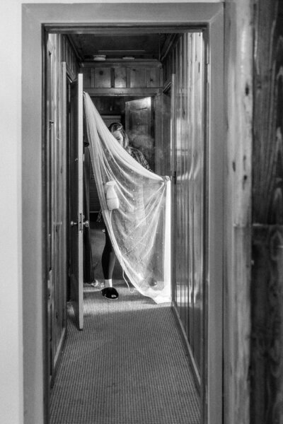 Black and white image of a woman spraying a wedding veil, representing the documentary style of Eugene Wedding photographer, Among the Oaks. 