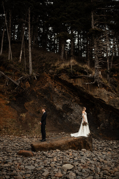 bride and groom standing on a big rock facing away from each other