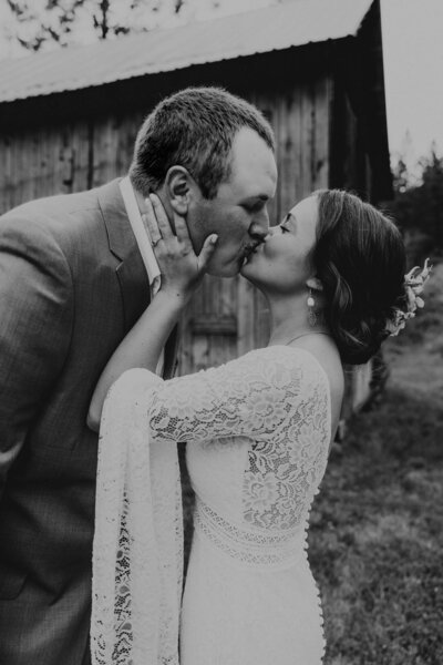 A candid moment of a bride and groom during their wedding in North Idaho, captured by Hannah Jo Photography. Bride and groom sneaking a kiss in North Idaho on their wedding day.