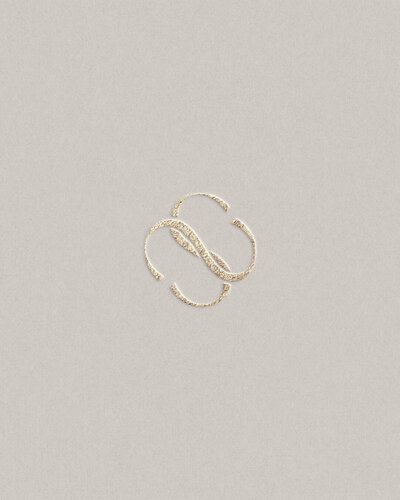 Elegant monogram logo design with intertwined gold initials on neutral background, showcasing timeless branding.