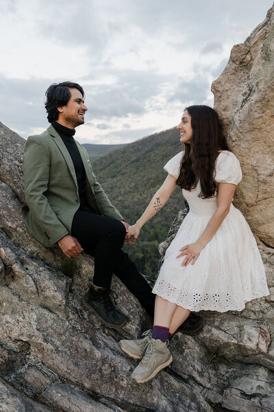 Newlyweds sitting on rocks holding hands