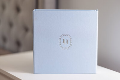 Light blue heirloom wedding album with Heritage House emblem on cover, displayed on a clean surface.