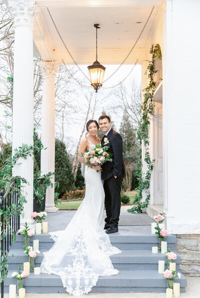 Bride and Groom pose for wedding portraits standing on front porch of white wedding venue. Taken at Ceresville Mansion in Frederick, Maryland.