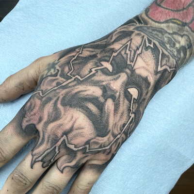 A black and gray tattoo of a moose skull with other decorative elements.