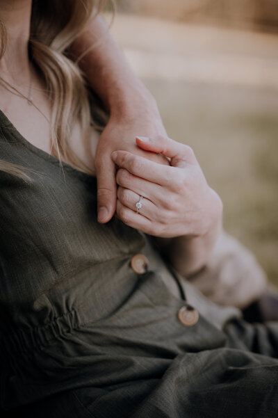Close up of couple holding hands with Engagement ring on display