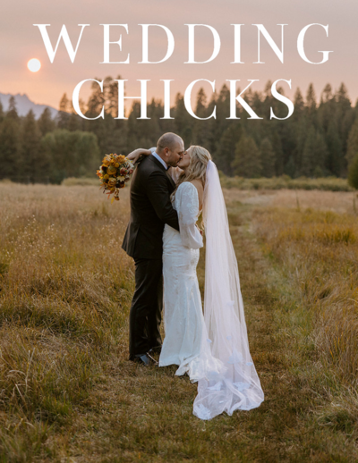 Bride and groom kissing in an open field during sunset, bathed in warm golden light.