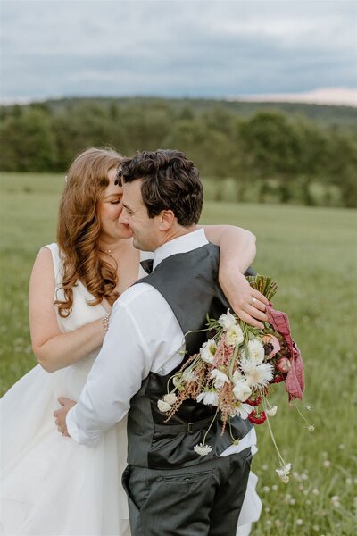two brides holding hands and walking through field next to water