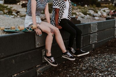 2 teens, one white girl and one black make sitting on wall in black and white