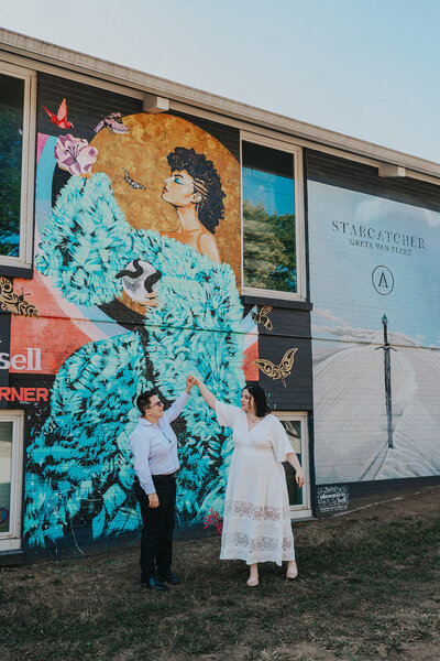 Person twirls their partner in front of a record store mural