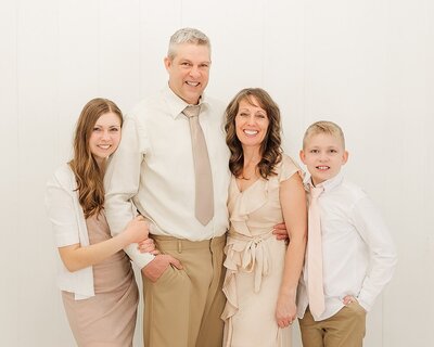 Family of JHP Team members standing close together by a white wall in a white studio.